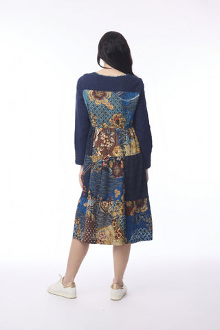 Woman wearing a navy blue long-sleeve midi dress with a colorful floral patchwork pattern.