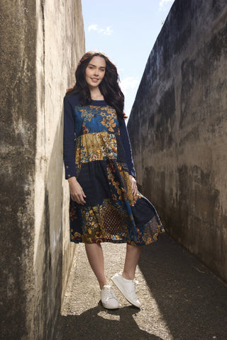 Woman wearing a navy blue long-sleeved patchwork floral midi dress and white sneakers.
