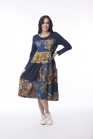 Woman wearing a navy blue long-sleeved patchwork floral midi dress and white sneakers.