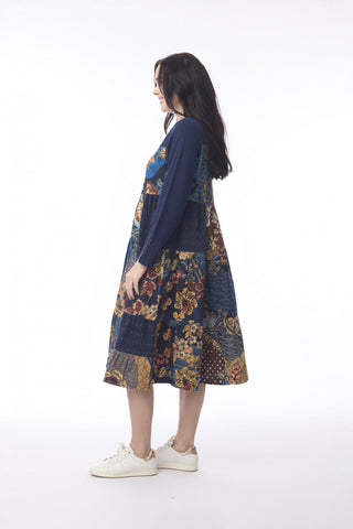 Woman wearing a navy blue midi dress with colorful floral patchwork patterns.