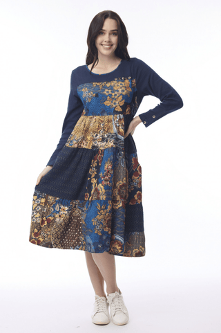 Woman wearing a navy blue long-sleeve patchwork floral midi dress and white sneakers.