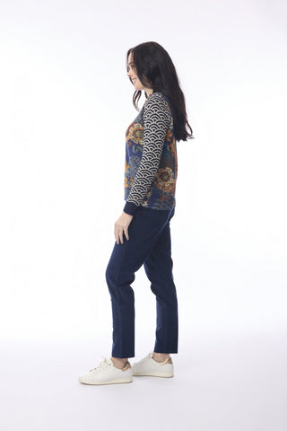 Woman wearing a patterned knit sweater and navy blue trousers with white sneakers.