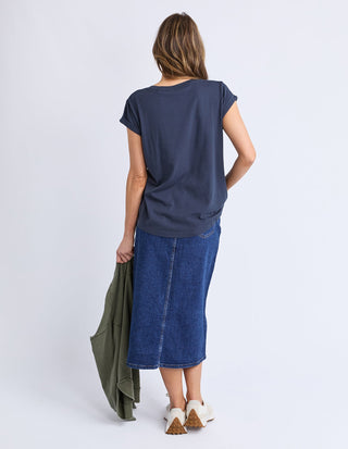 Woman from behind wearing a navy blue t-shirt and a denim midi skirt.
