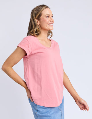Woman wearing a pink v-neck short sleeve t-shirt and blue denim skirt