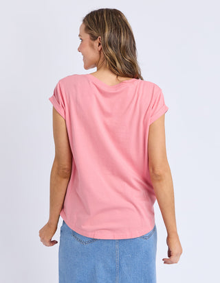 Back view of a woman wearing a pink short sleeve t-shirt and a denim skirt