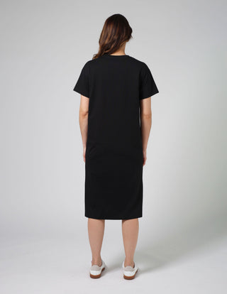 Woman wearing a black midi t-shirt dress standing against a grey background