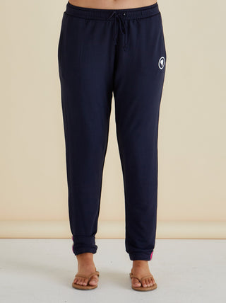 Navy blue drawstring jogger pants with white heart logo and pink trim detail.