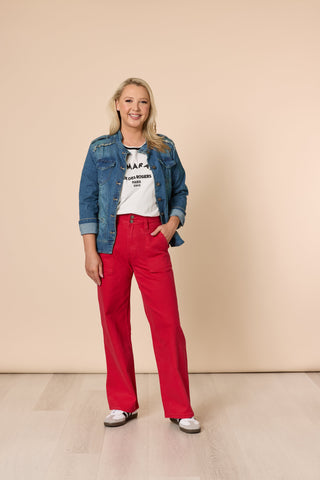 Woman wearing a blue denim jacket, white t-shirt, and red wide-leg pants.