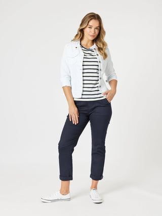 Woman wearing a light denim jacket, striped t-shirt, and navy blue cropped pants with white sneakers.