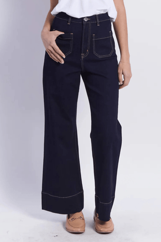 Woman wearing dark navy wide leg denim trousers with contrast stitching.