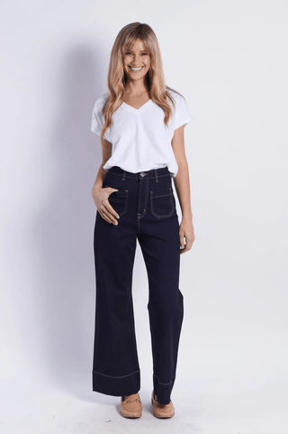 Woman wearing a white v-neck t-shirt and navy blue wide-leg denim pants.