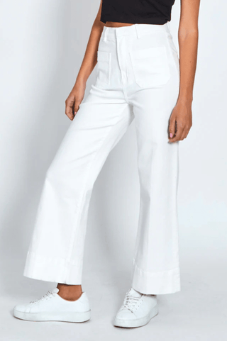 Woman wearing high-waisted white wide-leg pants and white sneakers.