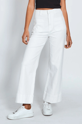 Woman wearing high-waisted white wide-leg pants and white sneakers