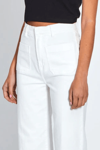 Woman wearing high-waisted white wide-leg denim pants and a black crop top.