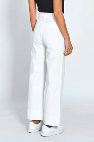 Woman wearing white high-waisted wide leg trousers and white platform sneakers.