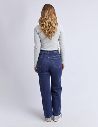 Woman wearing a grey long sleeve top and dark blue denim wide leg jeans.