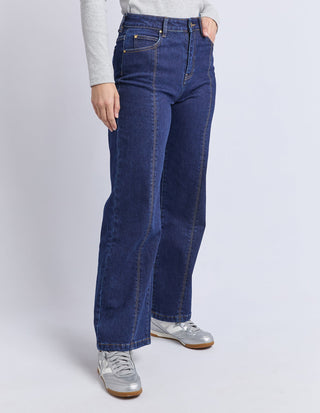 Woman wearing high-waisted wide leg dark blue denim jeans and silver sneakers
