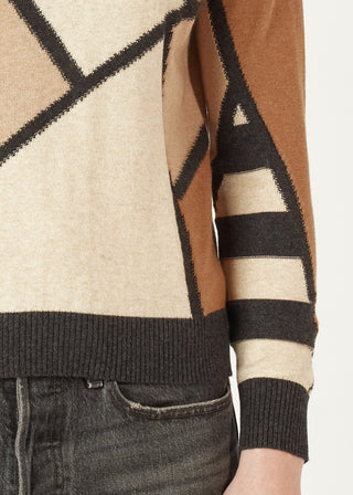 Woman wearing a geometric pattern knit sweater in beige, brown, and black tones.