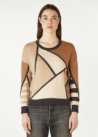 Woman wearing a geometric pattern knit sweater in tan, brown, and cream tones.