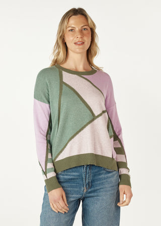 Woman wearing a multi-colored geometric pattern knit sweater in green, pink, and cream.