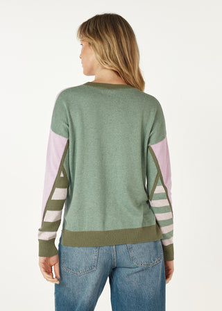 Woman wearing a sage green long sleeve knit sweater with pink and striped sleeve details.