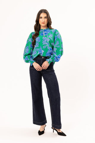 Woman wearing a green and blue floral print blouse with dark wash wide-leg jeans.