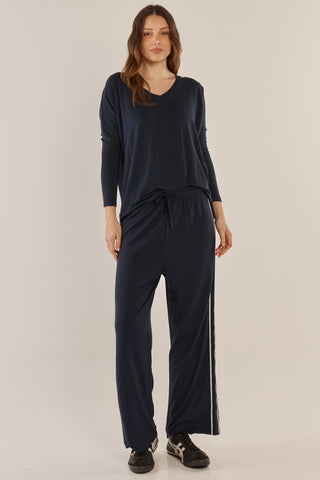 Woman wearing a navy blue long sleeve top and matching wide leg leisure pants with side stripes.