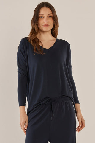 Woman wearing a navy blue long sleeve v-neck top and matching lounge pants.