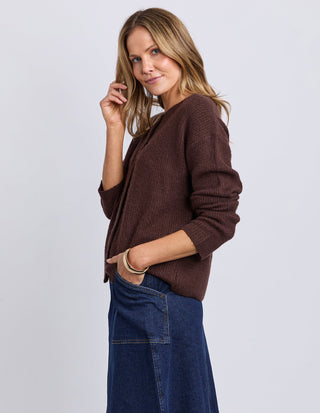 Woman wearing a brown ribbed knit cardigan and a blue denim midi skirt.