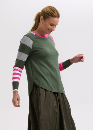 Woman wearing a green multi-patterned sweatshirt and olive green skirt.