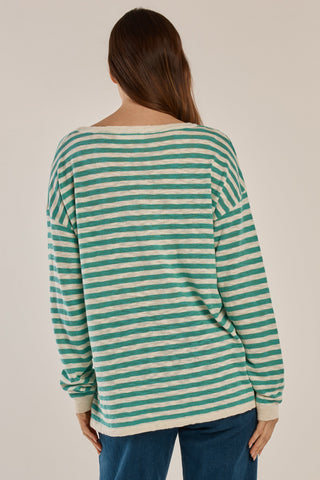 Woman wearing a teal and white striped long sleeve sweatshirt and blue jeans.
