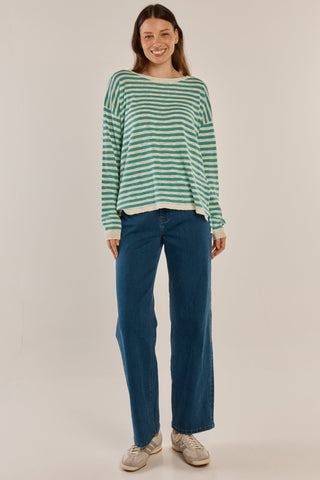 Woman smiling in a green and white striped long sleeve top and blue wide-leg jeans.