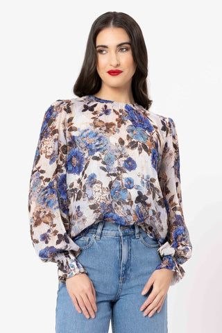 Woman wearing a blue and brown floral print blouse with light wash blue jeans