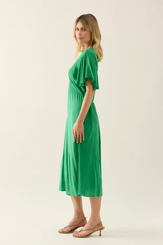 Woman wearing a bright green flutter sleeve midi dress and gold strappy heels.