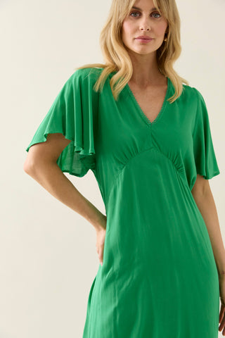 Woman wearing a vibrant green V-neck dress with flutter sleeves.