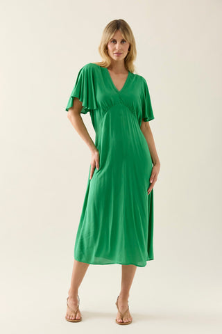 Woman wearing a green v-neck midi dress with flutter sleeves and gold strappy heels.