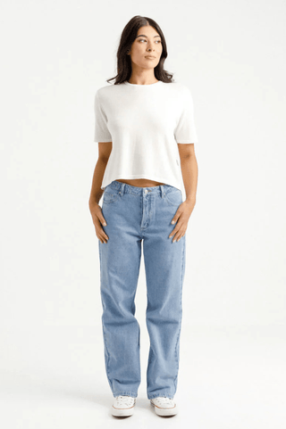 Woman wearing a white cropped t-shirt and light wash wide leg jeans with white sneakers.