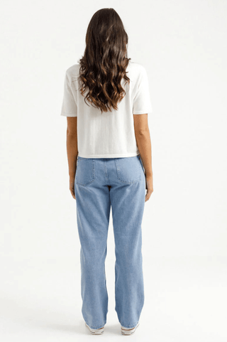 Back view of a woman wearing a white t-shirt and light blue wide-leg jeans.