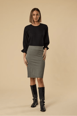 Woman wearing a black long sleeve blouse, grey pencil skirt, and black knee-high boots.