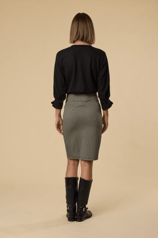 Woman wearing a black long-sleeve top, grey textured skirt, and black knee-high boots.