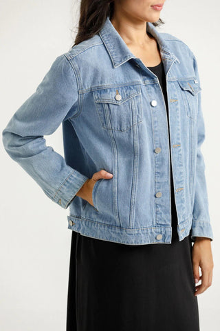 Woman wearing a light blue denim jacket over a black dress
