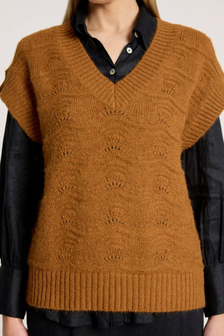 Woman wearing a brown textured knit v-neck vest over a black button-down shirt.