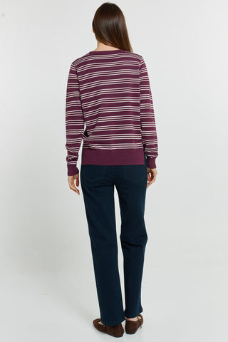 Back view of a woman wearing a burgundy striped sweatshirt and dark blue trousers.