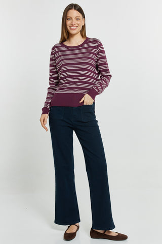 Woman wearing a maroon striped long sleeve top and navy wide leg pants with brown flats.