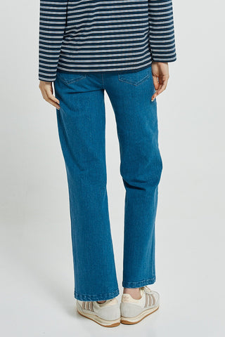 Woman wearing a blue and white striped top with straight-leg blue jeans and white sneakers.