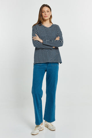 Woman wearing a navy and white striped long sleeve top and blue straight leg jeans.
