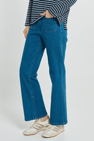 Woman wearing blue flare jeans, a striped top, and white sneakers.