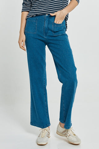 Woman wearing blue high-waisted wide-leg jeans and white sneakers.