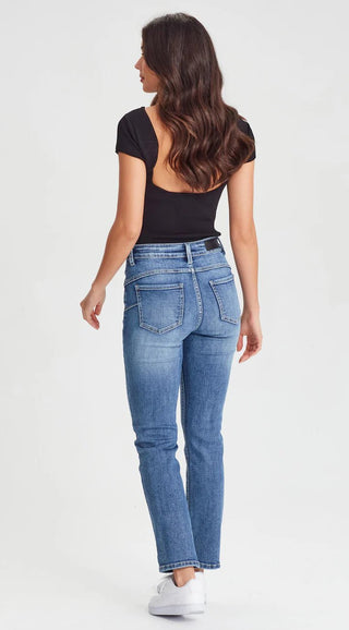 Woman wearing a black short-sleeve top and blue denim skinny jeans.