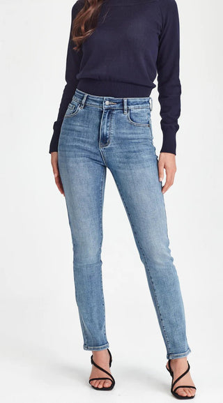 Woman wearing a navy blue long-sleeve top and light blue skinny jeans with black heels.